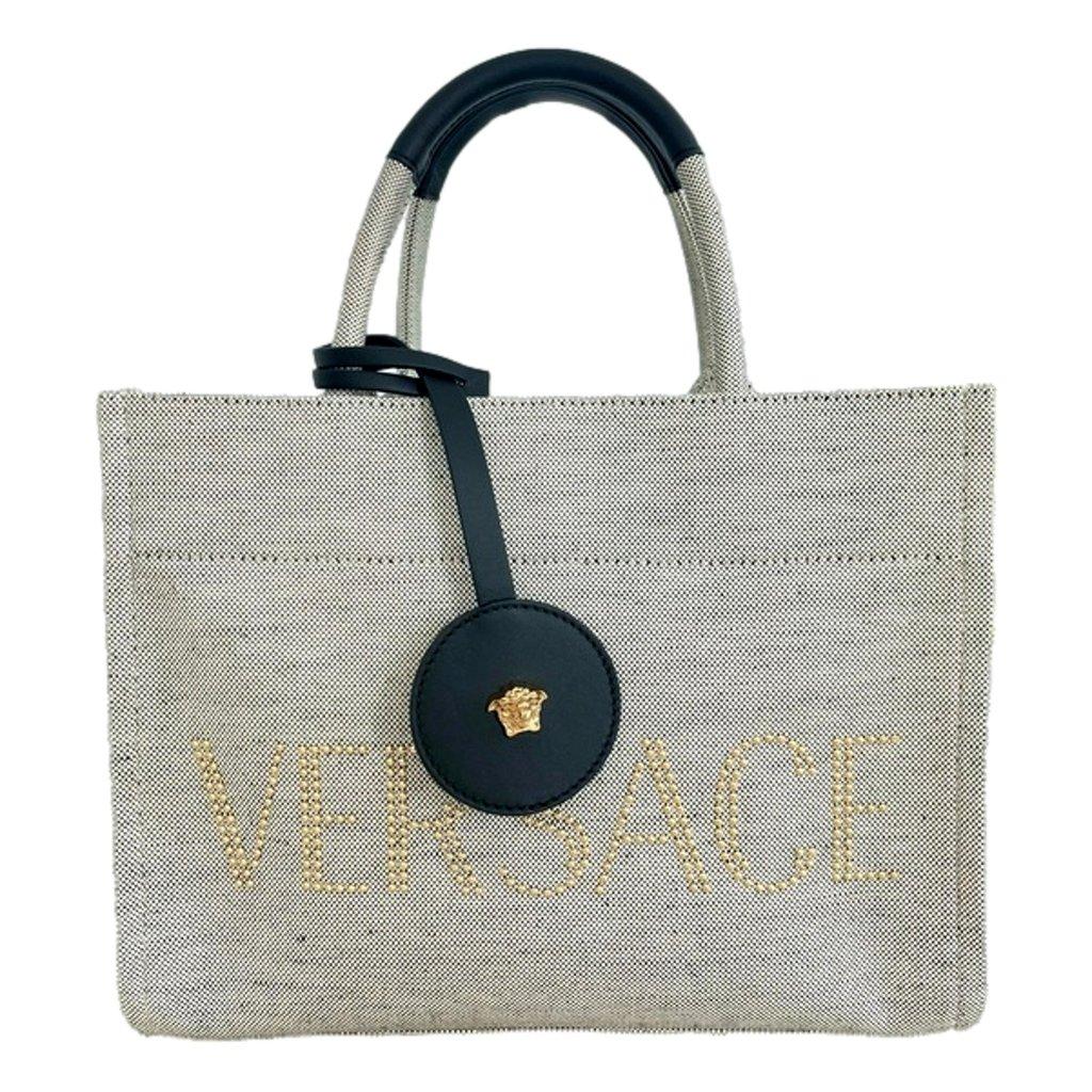 Versace حقيبة كروس صغيرة من قماش الكانفاس بلون بيج مرصعة بشعار فيرساتشي، مزودة بإكسسوارات ذهبية اللون.